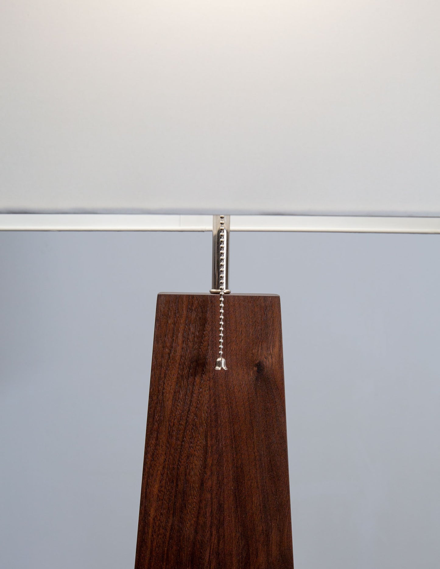 A close-up detail shot of the hand-built Snyder DePass Pas Floor Lamp, focusing on the seamless joinery of the solid wood body and the integrated cord design.