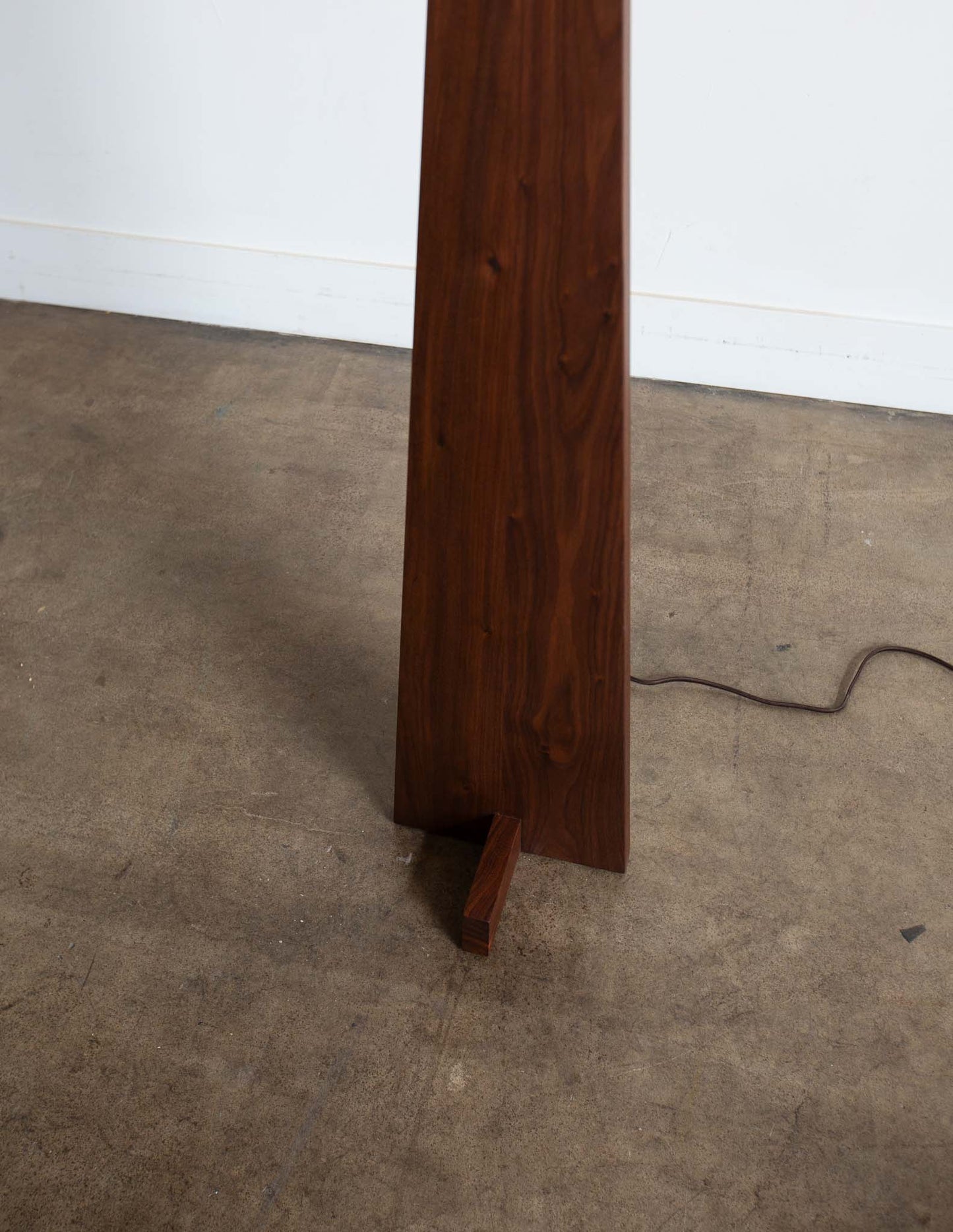 A close-up detail shot of the hand-built Snyder DePass Pas Floor Lamp, focusing on the seamless joinery on the front of the solid wood body, which highlights the sculptural design.