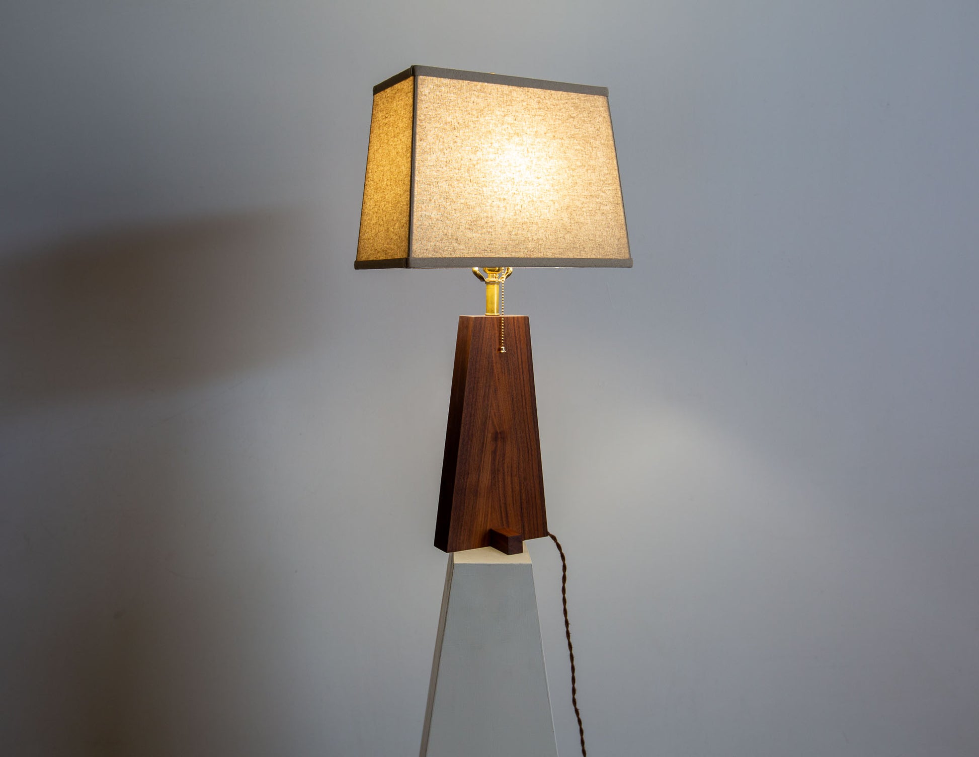 A hand-built Snyder DePass Pas Lamp, featuring a unique, asymmetric design with a solid wood body and a clean, sculptural silhouette.