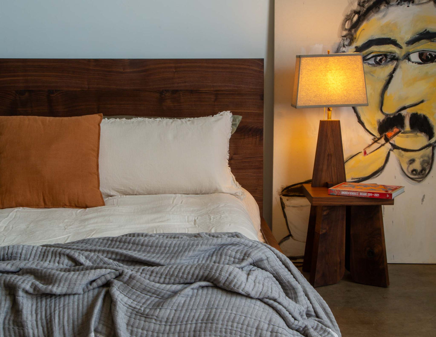 A full view of the Snyder DePass Mel Bed in a bright, modern bedroom. The bed, crafted from solid Walnut, features a low profile and a floating design, creating an open and minimalist feel.