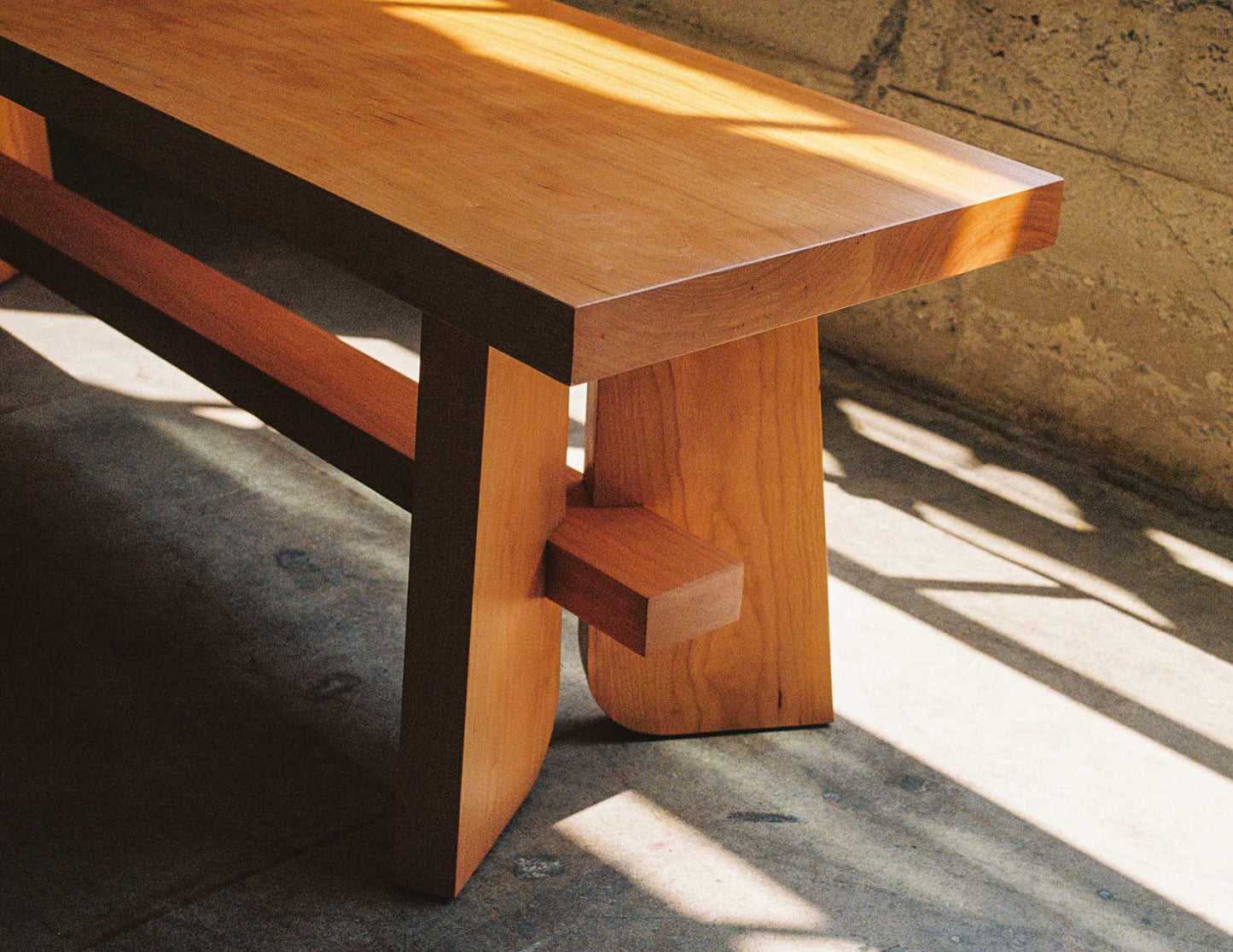 A detail photo of a hand-built Snyder DePass Temple Bench. The solid Cherry bench features a minimalist, contemporary design, showcasing the natural beauty of the wood.