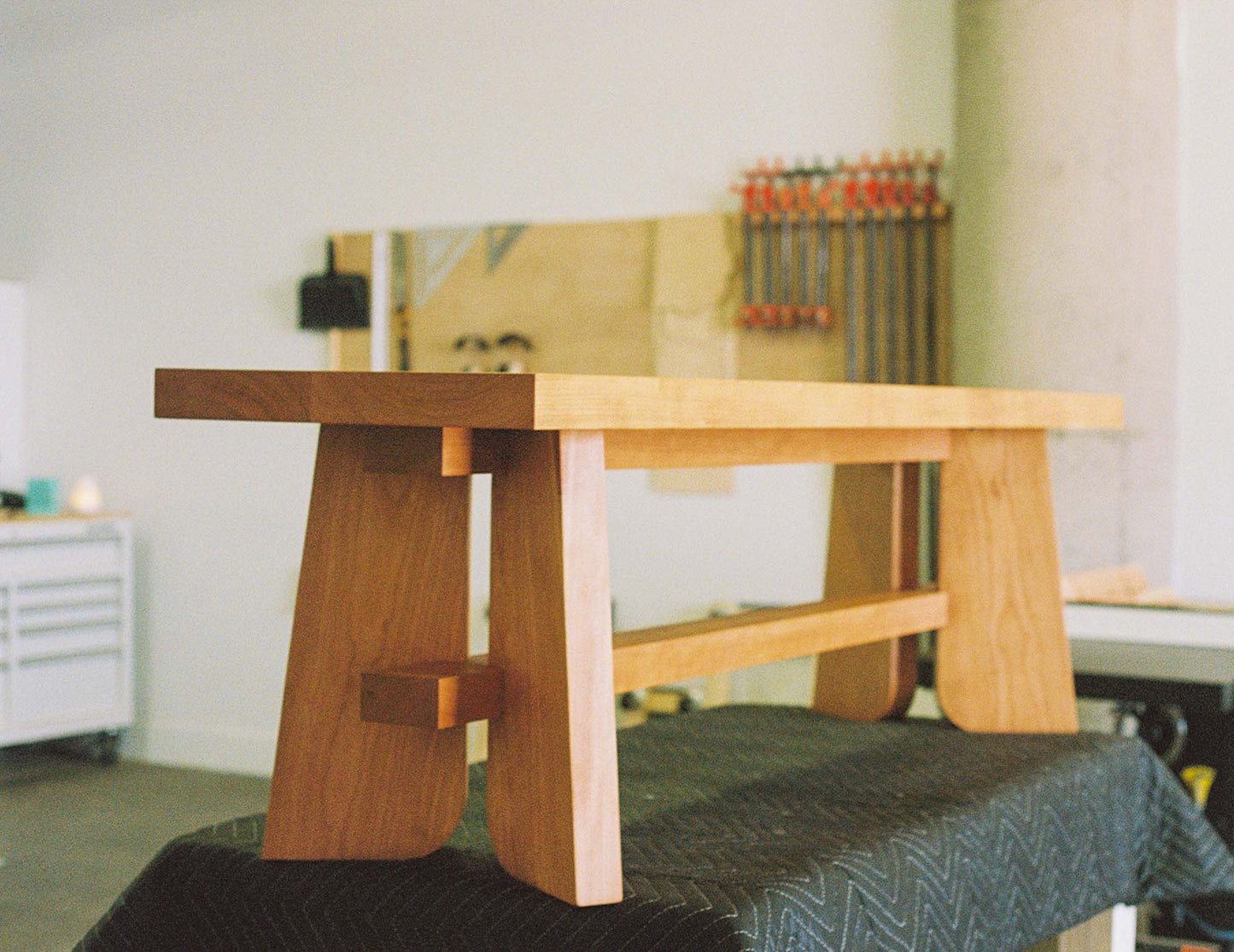 A detailed shot of the hand-built Snyder DePass Temple Bench, showcasing the smooth, solid Cherry frame and the elegant, minimalist joinery from a different angle.