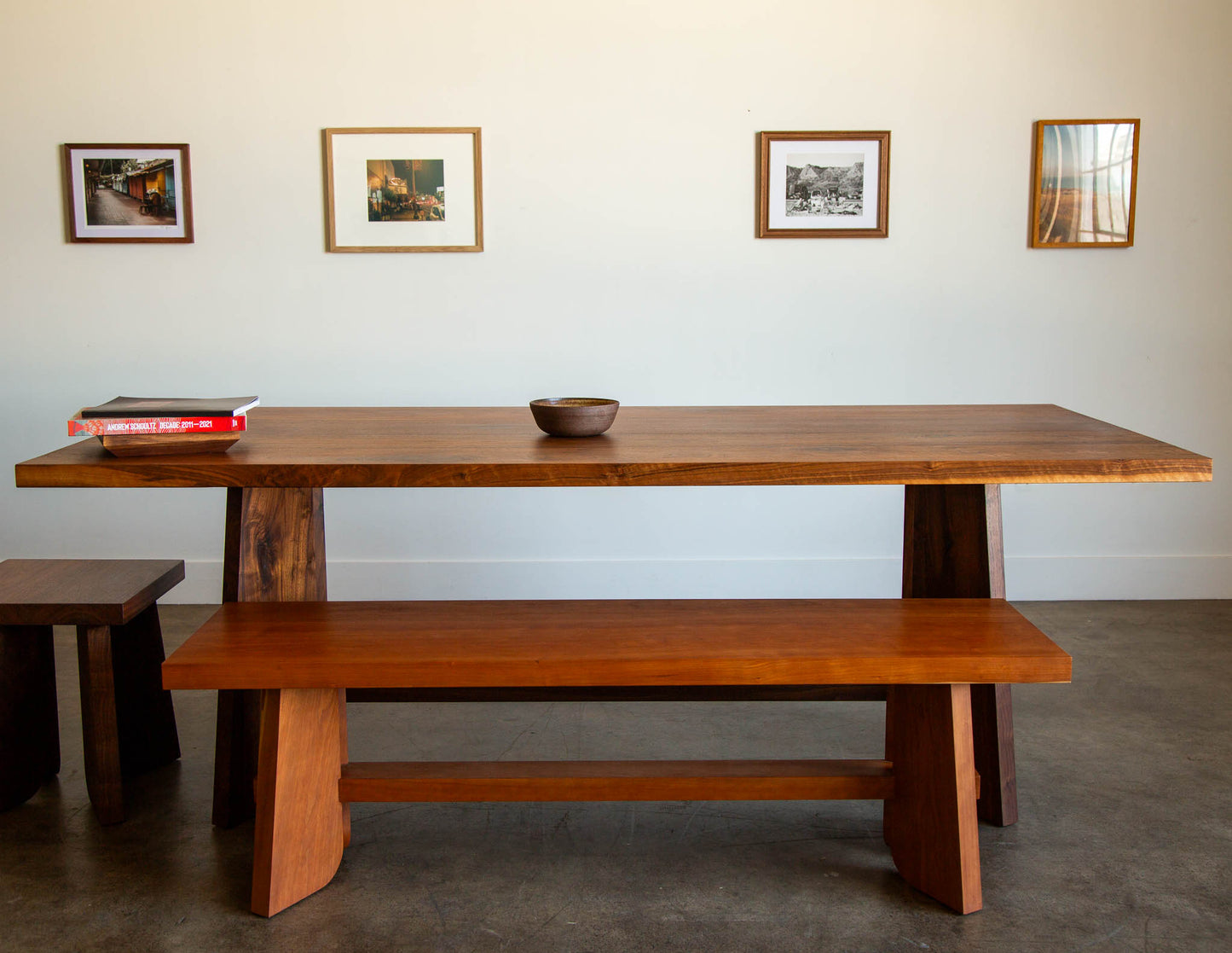 A lifestyle shot featuring multiple pieces from the Snyder DePass Temple Collection, including a bench, stool, and dining table, all hand-built from solid Walnut and Cherry with a clean, contemporary design.