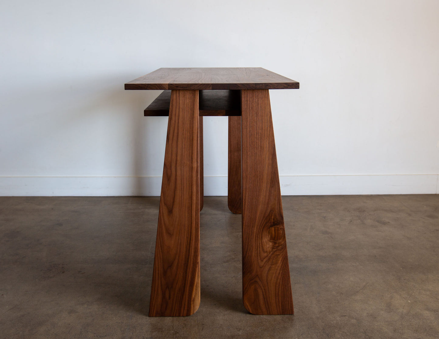 A side view of the hand-built Snyder DePass Walnut Temple Desk, highlighting the clean, minimalist lines of the solid wood construction and the subtle details of the craftsmanship.