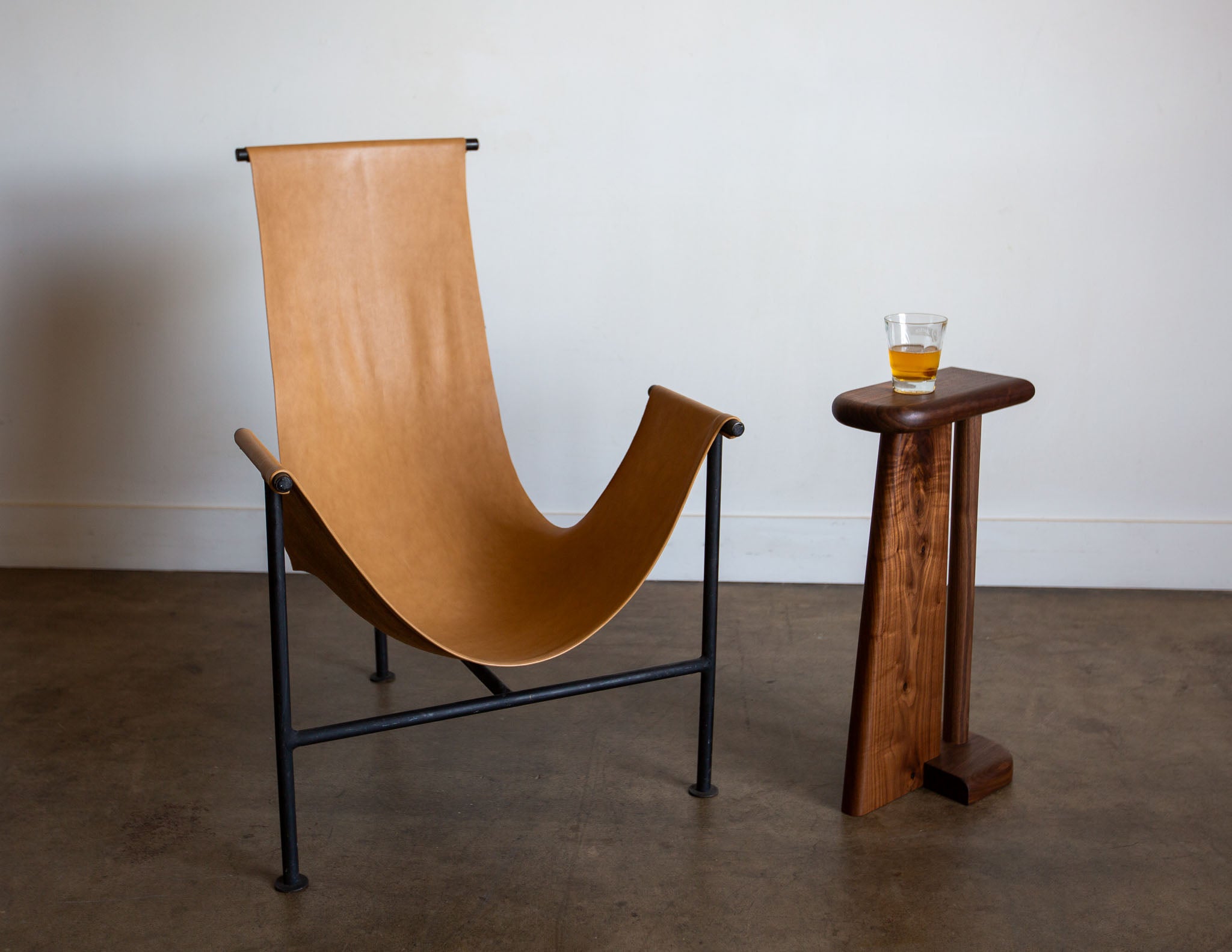 The hand-built Snyder DePass Walnut Drink Stand is shown with a chair, highlighting its functional use as a minimalist and elegant side table.