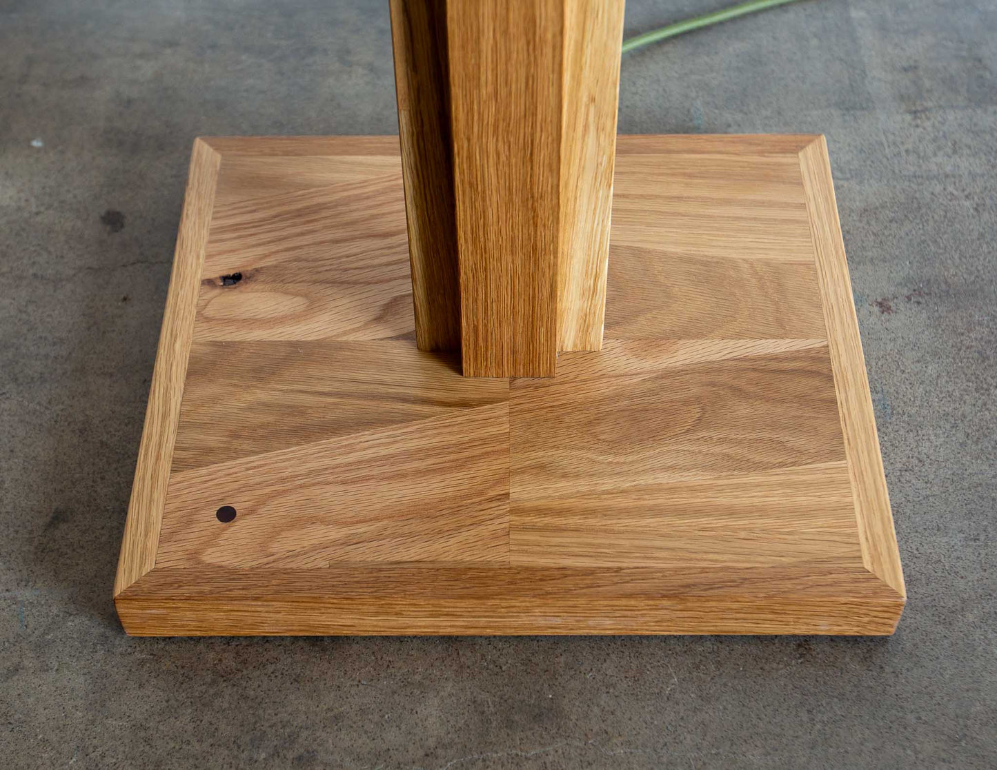 A close-up detail shot of the base of the Snyder DePass Layered Floor Lamp, showing the seamless connection between the tiered wood and the sturdy, clean lines of the design.