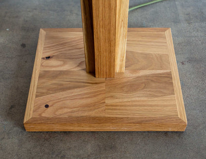 A close-up detail shot of the base of the Snyder DePass Layered Floor Lamp, showing the seamless connection between the tiered wood and the sturdy, clean lines of the design.