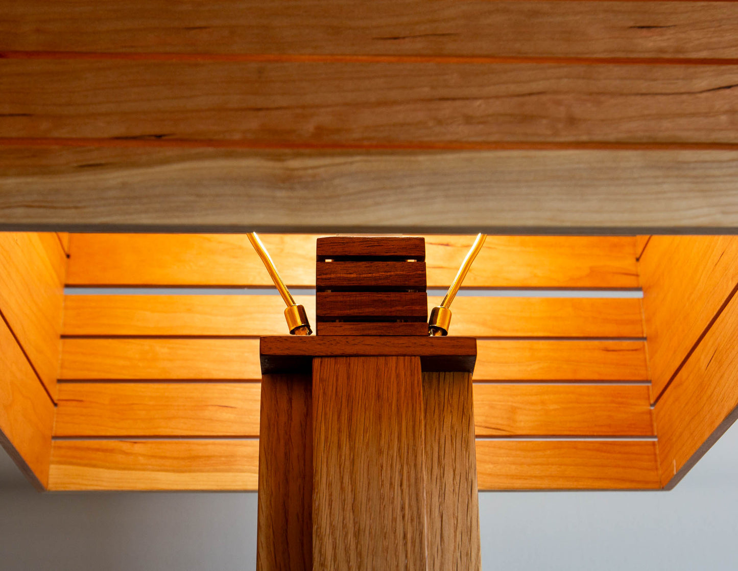 A close-up detail shot of the top of the Snyder DePass Layered Floor Lamp, showing the custom-machined brass socket cover and the seamless wood joinery.