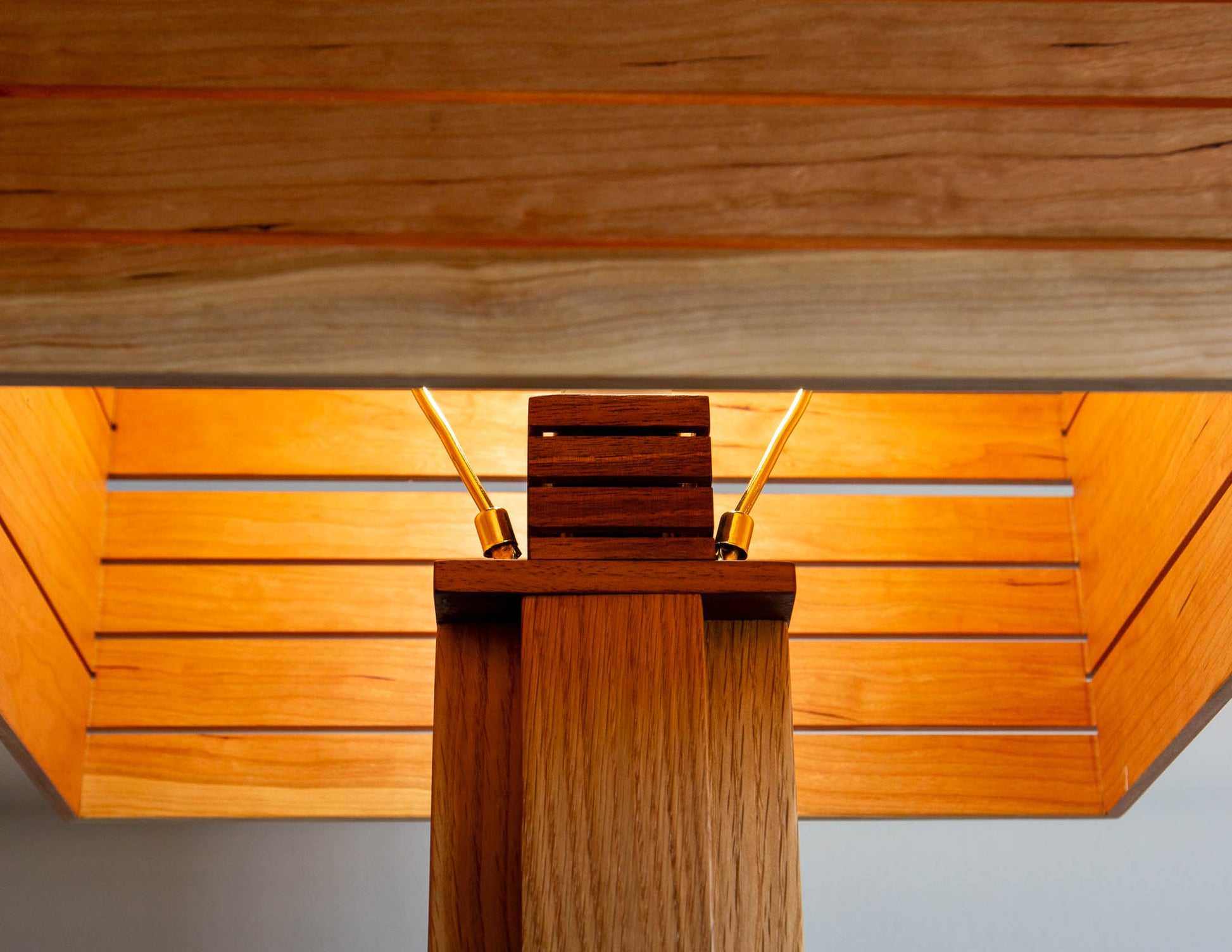 A close-up detail shot of the top of the Snyder DePass Layered Floor Lamp, showing the custom-machined brass socket cover and the seamless wood joinery.