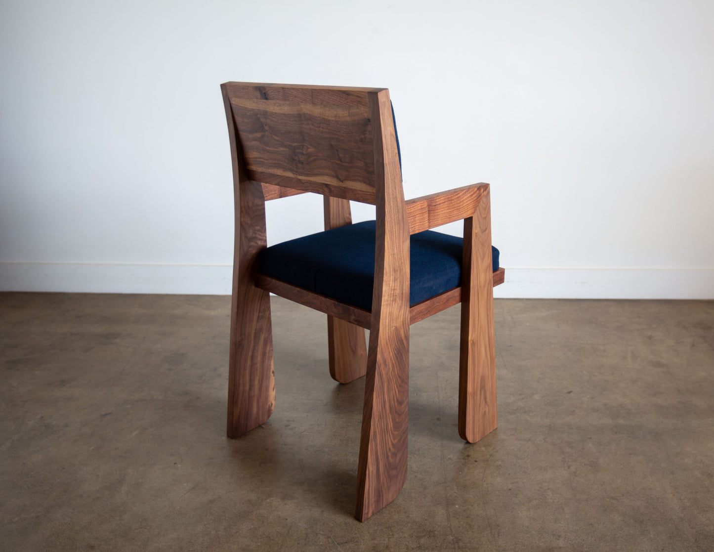 A back view of the hand-built Snyder DePass Walnut Temple Upholstered Chair, highlighting the seamless joinery of the solid walnut frame and the clean lines of the design.