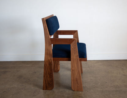 A side view of the hand-built Snyder DePass Walnut Temple Upholstered Chair, highlighting the seamless joinery of the solid walnut frame and the clean lines of the design.