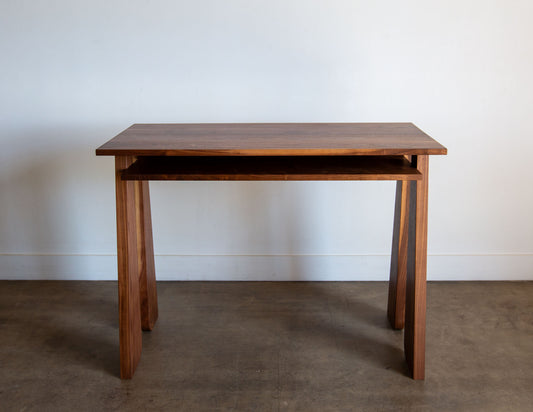 A straight-on view of the hand-built Snyder DePass Walnut Temple Desk, showing the clean, minimalist design of the tabletop and legs, and the rich grain of the solid wood.